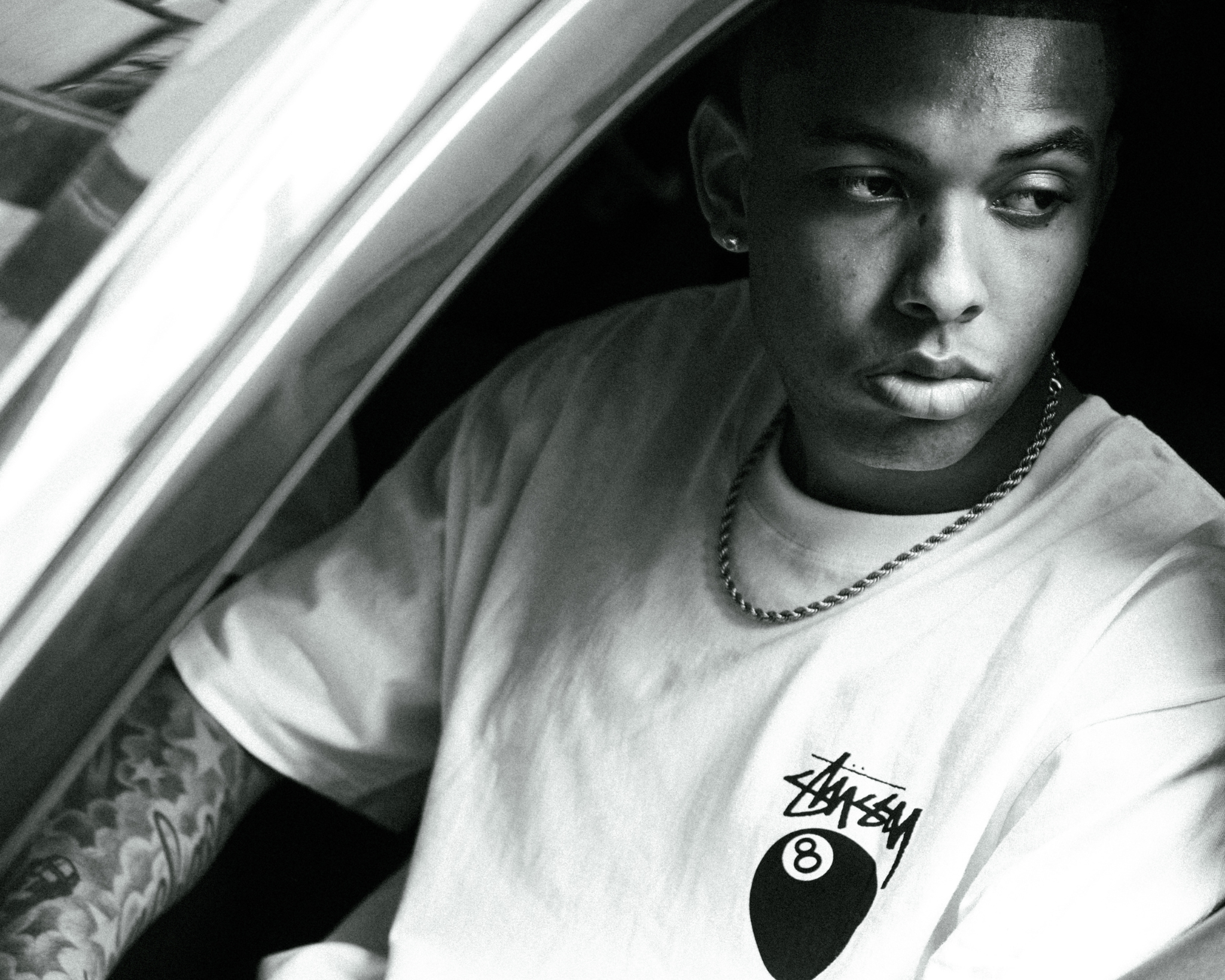 Mand med Stussy 8-ball t-shirt og tatoverede arme