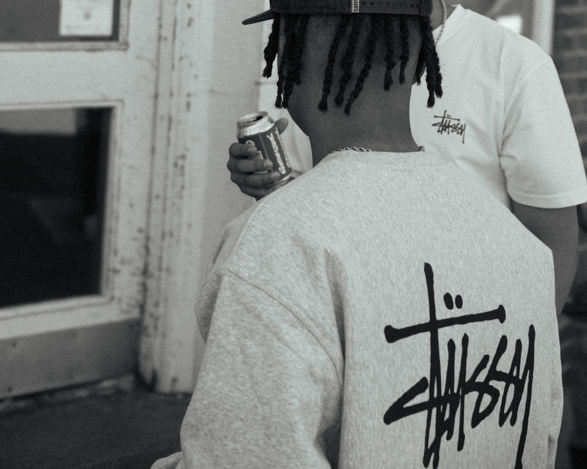 Ung mand i Stussy sweatshirt, drikker energidrik, streetwear billede.