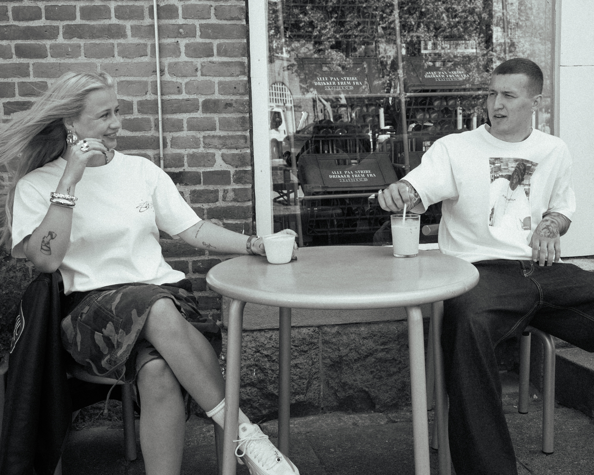 model iført stussy t-shirt og beanie udenfor et sted i byen med drikkevarer